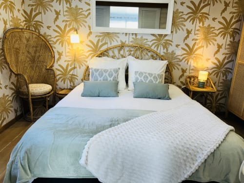 Chambre de la Bounty cottage à La Villa Plein Vent avec papier peint tropical, chaise tissée et vue sur le jardin