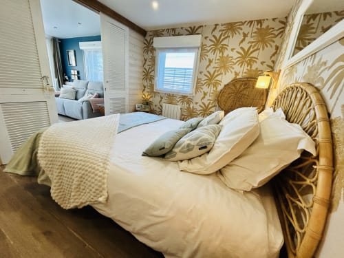 Chambre côtière de La Villa Plein Vent avec lit en rotin, papier peint botanique et vue sur l'océan à Barneville-Carteret