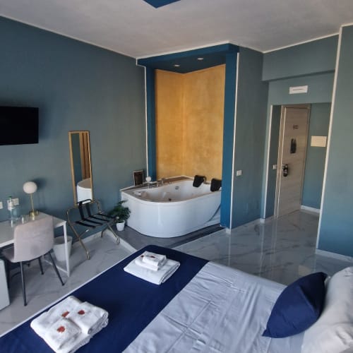 Camera da letto moderna con vasca idromassaggio di lusso presso U Baruni B&B a Messina, Italia. Pareti blu, pavimento in marmo e design contemporaneo