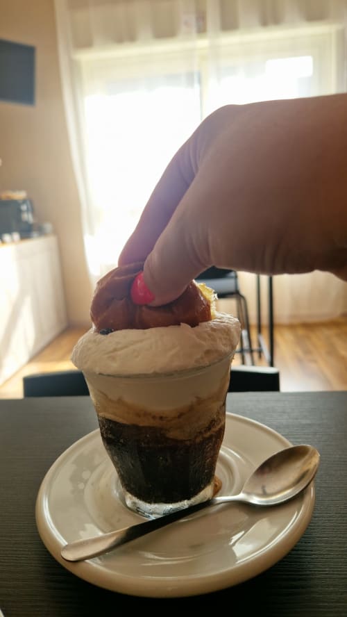 Mano che regge il dolce al cioccolato e panna a strati presso U Baruni b&b a Messina, Italia