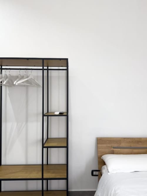 Camera moderna presso I colori di Napoli Napoli, con letto in legno e guardaroba minimalista con cornice nera e ripiani
