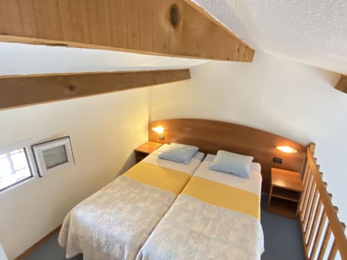 Dormitorio acogedor en la casa rural Domaine de la Bégude, Fayence con camas gemelas, cabecero de madera, lámparas de noche y comodidades modernas