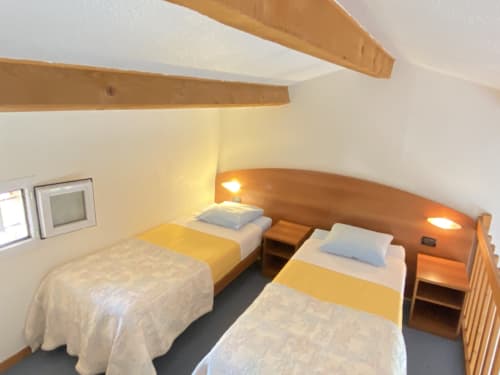 Chambre twin du gîte Domaine de la Bégude à Fayence, avec poutres apparentes et éclairage chaleureux
