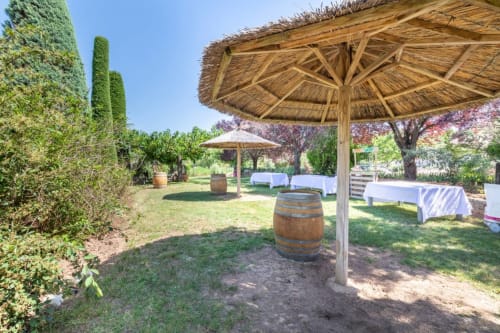 Área de jardín al aire libre en el Domaine de la Bégude en Fayence con pérgola de madera, barril de vino, hiedra y mesa vestida