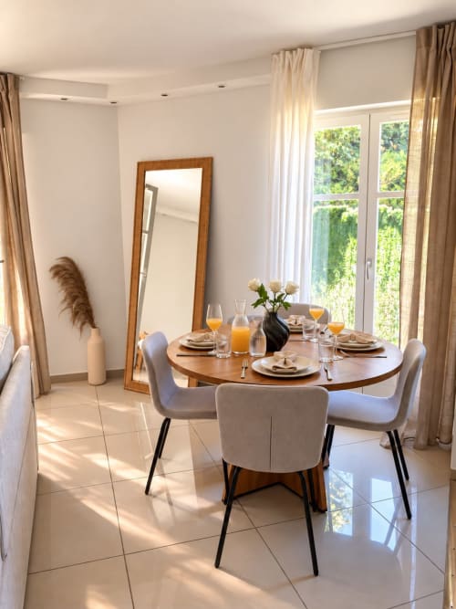 Salle à manger lumineuse du Paradis Des Logis avec table ronde en bois, vue jardin par portes vitrées et mobilier moderne
