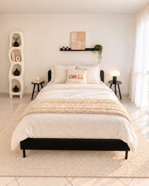 Chambre moderne au Paradis Des Logis avec lit à cadre noir, draps blancs, étagère murale crème et lumière naturelle