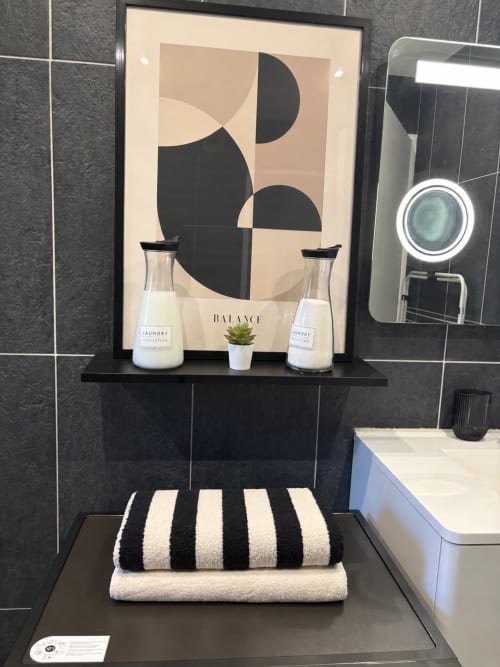 Étagère de salle de bain moderne avec art géométrique noir et crème, flacons de linge, plante succulente et serviettes rayées