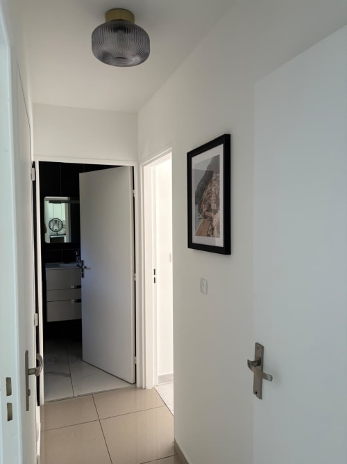 Couloir lumineux de l'appartement Le Paradis Des Logis à Pierrefitte-sur-Seine, avec œuvres d'art encadrées et équipements modernes