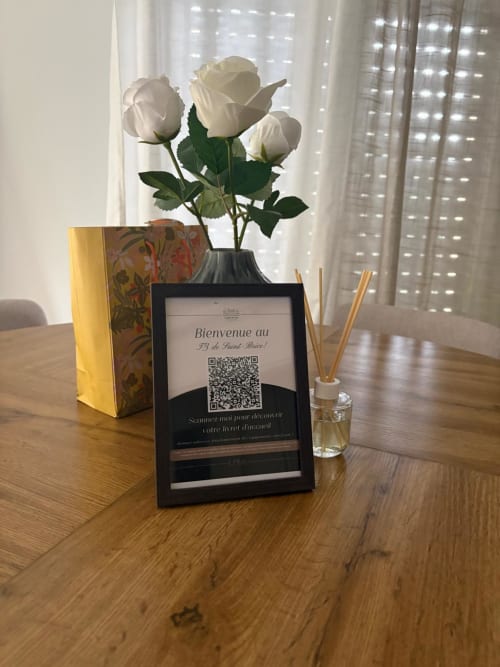 Cadre d'accueil avec roses blanches dans un vase noir sur bureau en bois à l'appartement Le Paradis Des Logis, Pierrefitte