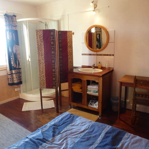 Chambre de Jonathan à La Ferme Buissonnière BnB à Biol, France avec meubles en bois, miroir rond et douche