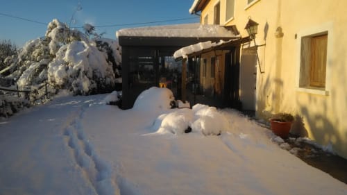 Entrée enneigée du gîte La Ferme Buissonnière à Biol avec vue sur les montagnes et paysage hivernal