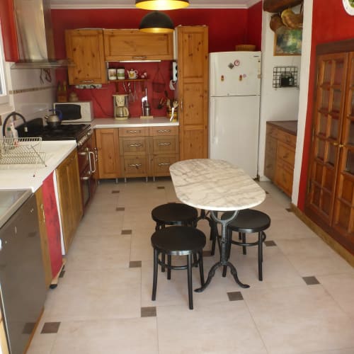 Cuisine rustique de La Ferme Buissonnière à Biol avec murs rouges, meubles en bois et coin repas.