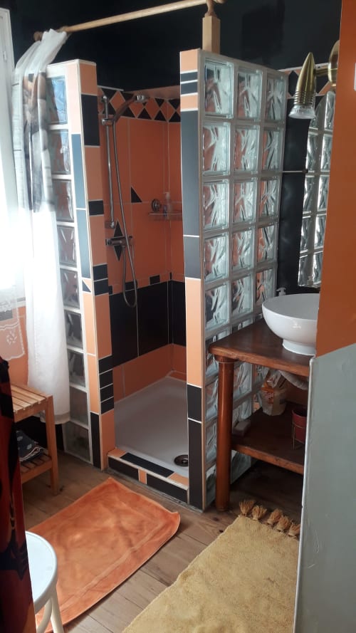 Salle de bain moderne du gîte La Ferme Buissonnière à Biol avec douche carrelée orange et séparation en briques de verre
