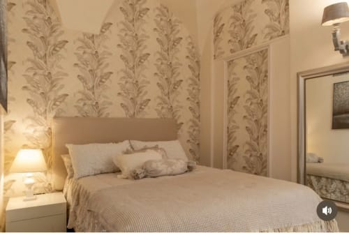 Camera elegante alle SEVEN SUITES SANREMO con carta da parati floreale beige, letto queen, illuminazione soffusa e specchio - Toffee Matteotti