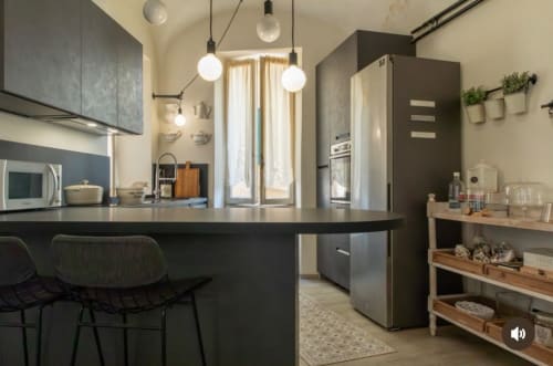 Cucina moderna dell'appartamento Toffee Matteotti presso Seven Suites Sanremo con mobili scuri, lampadari sospesi e acciaio inossidabile