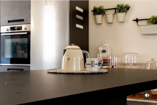Cucina moderna alle SEVEN SUITES SANREMO con bollitore SMEG color crema, macchina da caffè e erbe aromatiche in vasi su scaffali