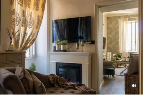 Elegante soggiorno dell'appartamento Toffee Matteotti alle SEVEN SUITES SANREMO con camino, TV a schermo piatto, divano marrone e