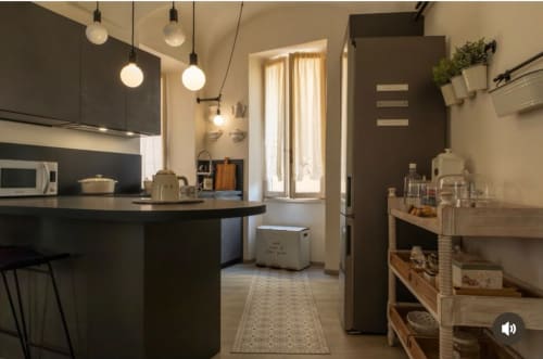 Cucina moderna dell'appartamento Toffee Matteotti presso SEVEN SUITES SANREMO con cabinetry scuro, illuminazione a sospensione e legno