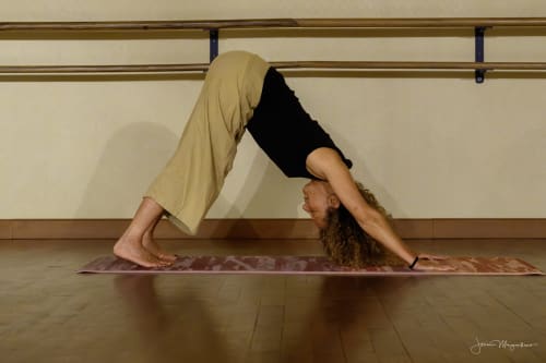 Yoga practitioner in downward dog pose on mat at Le Bacalan wellness studio in Mormoiron
