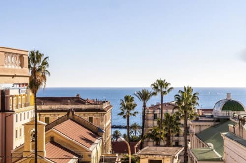 Vista costiera di Sanremo dall'appartamento Seven Suites con edifici mediterranei, palme e orizzonte marino