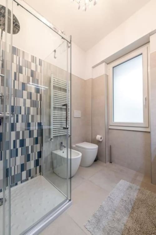 Bagno moderno dell'appartamento Toffee Casinò alle SEVEN SUITES SANREMO con cabina doccia in vetro e piastrelle blu