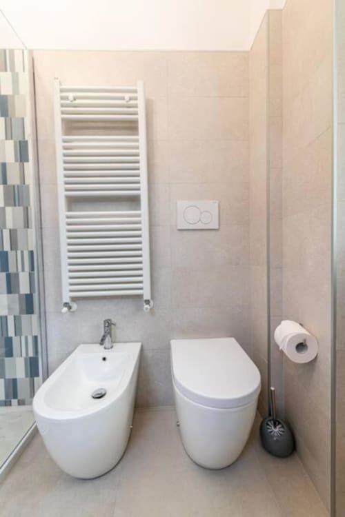 Bagno moderno dell'appartamento Seven Suites Sanremo con bidet, wc, scaldasalviette bianco riscaldato e dettagli piastrelle blu