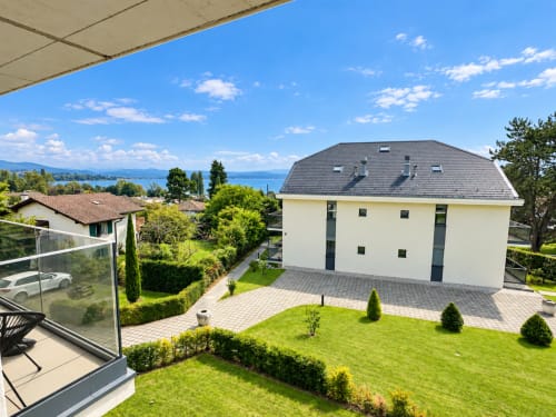 Maison contemporaine blanche avec toit gris dominant le lac à Attica Résidences à St-Sulpice, Suisse