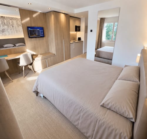Studio Attica Résidences à St-Sulpice avec vue sur lac, mobilier bois moderne, lit, bureau et TV