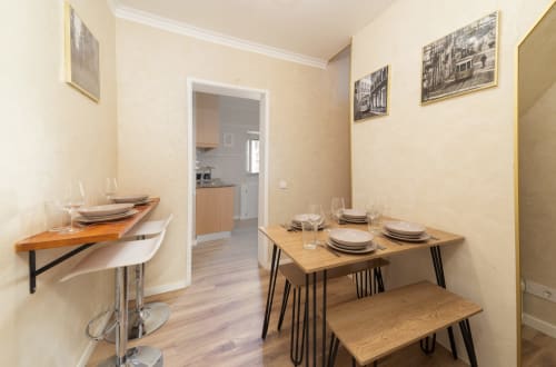 Dining area in Bica Mini Hostel apartment, Lisboa, with wooden table, place settings, and kitchen visible through doorway