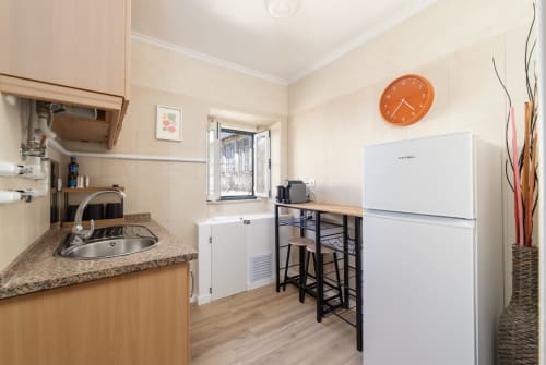 Modern kitchen and dining area in Bica Mini Hostel apartment, Lisboa with white refrigerator and bar seating