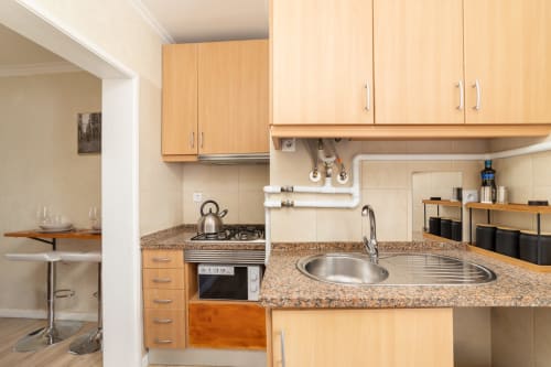 Modern kitchen with wood cabinets, granite counters, and sink in Bica Mini Hostel apartment, Lisboa