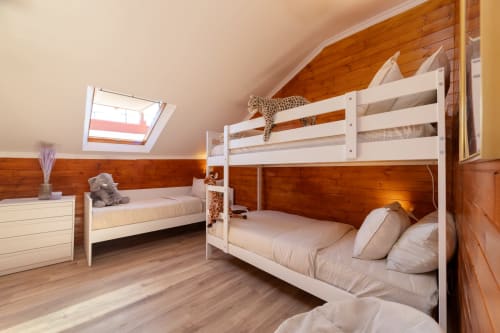 Spacious attic bedroom at Bica Mini Hostel, Lisboa, with white bunk beds, wooden beams, skylight, and accommodations for 6