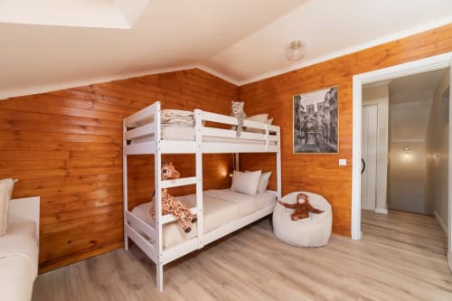 Bright children's bedroom at Bica Mini Hostel Lisboa with white bunk bed, wooden walls, and cream bean bag chair