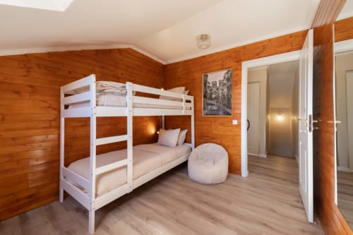 Modern hostel bedroom with white bunk beds, wood walls, and beige floor at Bica Mini Hostel Lisboa