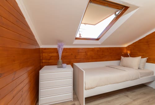 Bright loft bedroom at Bica Mini Hostel Lisboa with wooden walls, white bed, skylight, and modern furnishings