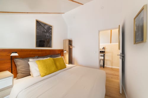 Bright bedroom in Lisbon Central Apartments with wooden bed frame, yellow pillows, and hardwood flooring
