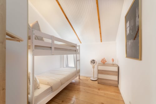 Modern hostel bedroom in Lisbon with white bunk bed, wood floors, and minimalist décor