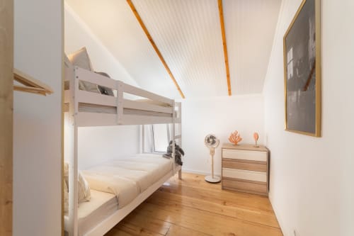 Modern hostel bedroom in Lisbon Central Apartments with white loft bed, wooden flooring, and minimalist décor
