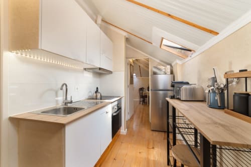 Modern kitchen in Lisbon Central Apartments hostel with white cabinets, stainless steel appliances, wooden counters, and