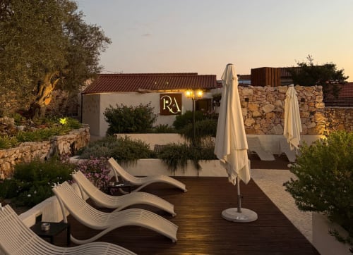 Terraço do hotel Recantos D'Almerinda ao entardecer com espreguiçadeiras, guarda-sóis e arquitetura em pedra em Pombal, Portugal