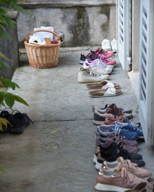 Shoe rack at Roseto del Drago B&B entrance in Ponte In Valtellina showing organized guest footwear and wicker storage basket