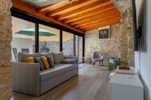 Elegante sala de estar moderna em Recantos D'Almerinda com paredes de pedra, vigas de madeira, sofá cinzento e vistas para o terraço em Pombal
