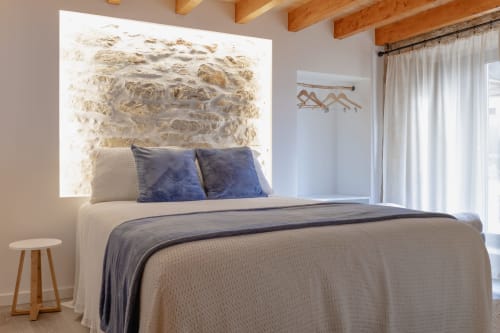 Quarto moderno em Recantos D'Almerinda com parede de pedra, almofadas azuis e vigas de madeira no teto em Pombal