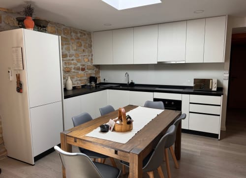 Cozinha moderna branca com bancada preta, mesa de jantar e parede de tijolos à vista em Recantos D'Almerinda em Pombal