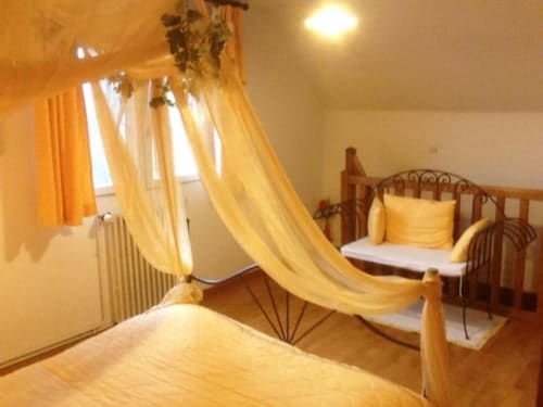 La chambre La Roue au Moulin De La Côte B&B à Saint Vigor avec lit à baldaquin jaune et mobilier en bois