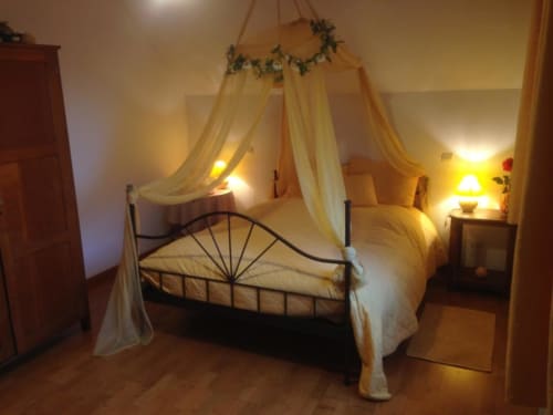 Lit à baldaquin romantique aux tentures crème et verdure à l'hôtel Le Moulin De La Côte, Saint Vigor, France