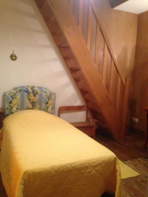 Chambre douillette au gîte Le Moulin De La Côte à Saint Vigor avec literie jaune, tête de lit fleurie et vue sur la rivière