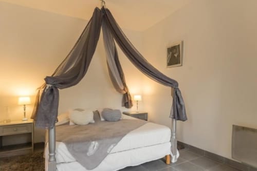 La chambre Le Cygne au Moulin De La Côte à Saint Vigor, avec son lit à baldaquin élégant et vue sur le jardin