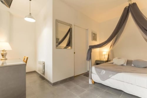 Chambre élégante au Moulin De La Côte avec lit à baldaquin, luminaires suspendus et vue sur jardin à Saint Vigor