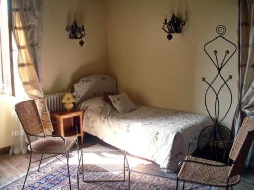Chambre douillette au Moulin De La Côte avec lit, fauteuils en rotin, décoration murale et vue sur le jardin à Saint Vigor